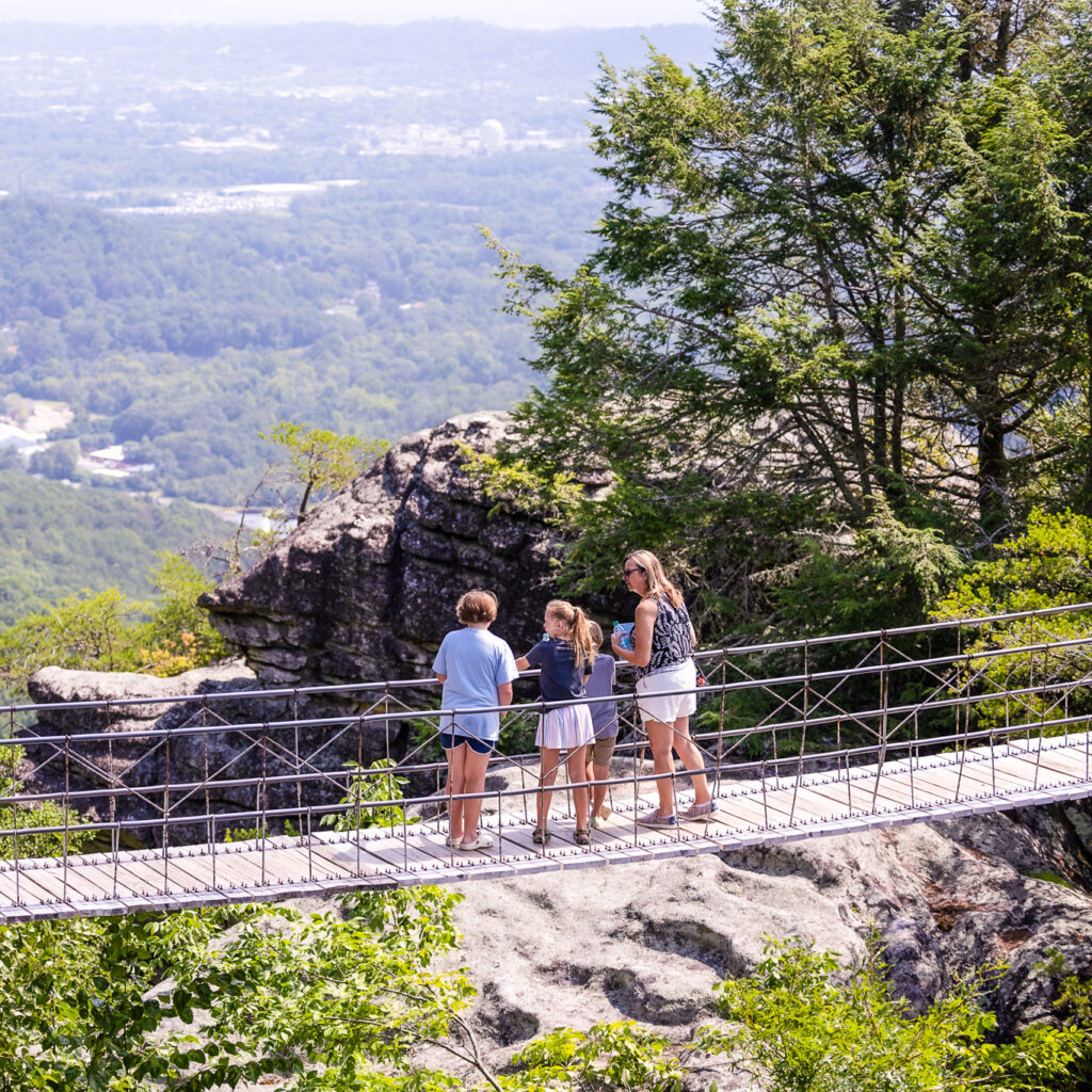 Family crossing the Swing-A-Long Bridge, a top Chattanooga tourist attraction with incredible mountain views.