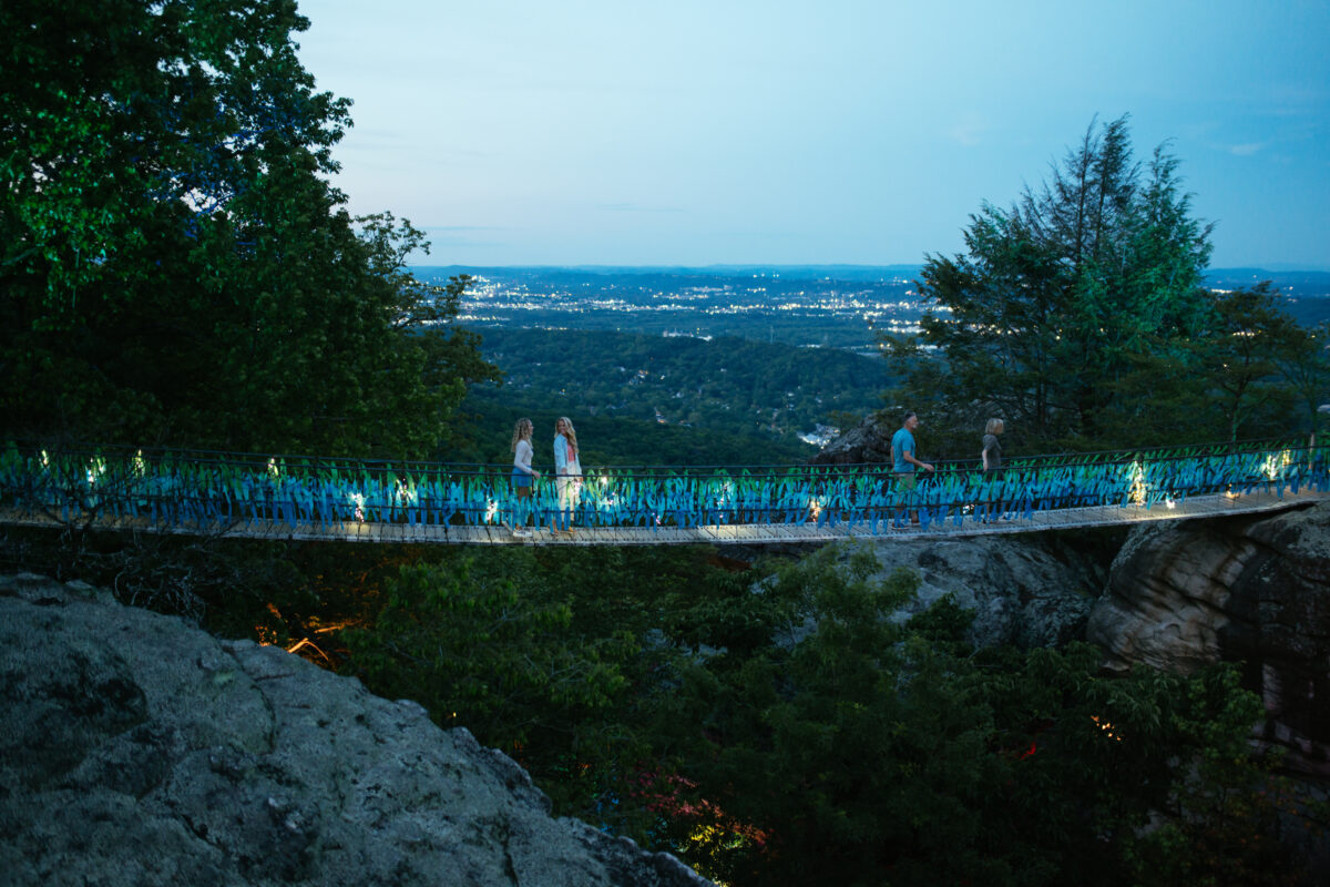 People on swinging bridge at Rock City at night.